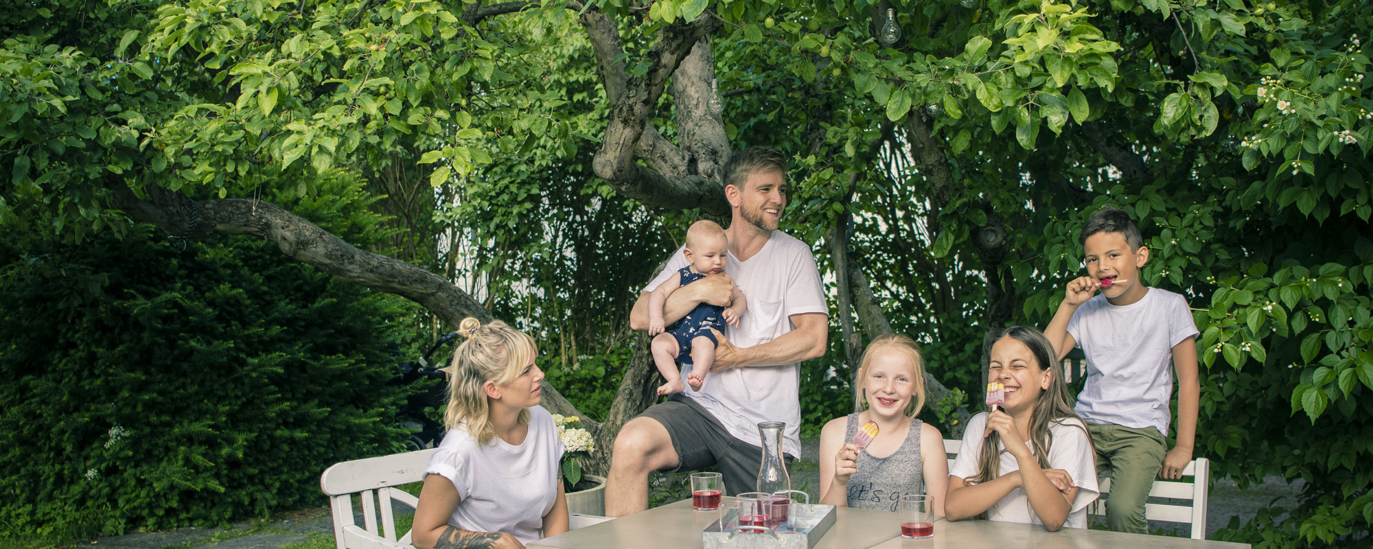 Familie på fem ved langbord drikker saft